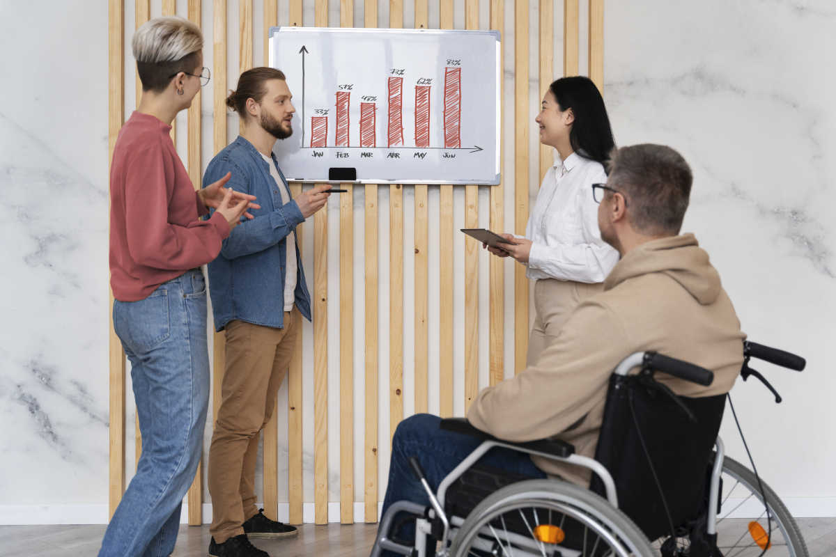 4 persone di cui uno disabile guardano un grafico a istrogrammi
